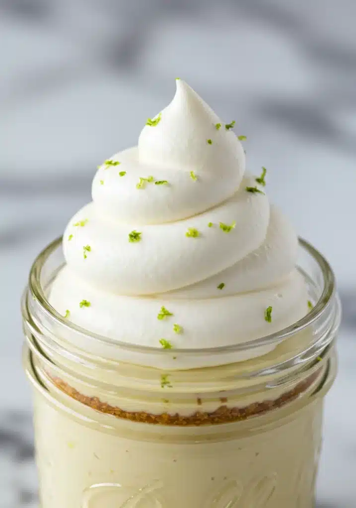 Macro shot of a swirl of whipped cream piped perfectly on top of a Key Lime Pie Jar