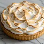 image of a whole lemon meringue pie on a marble surface.
